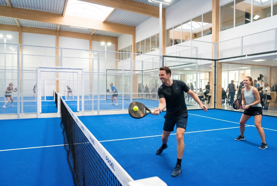 Mixed doubles at the net in a bright indoor padel hall